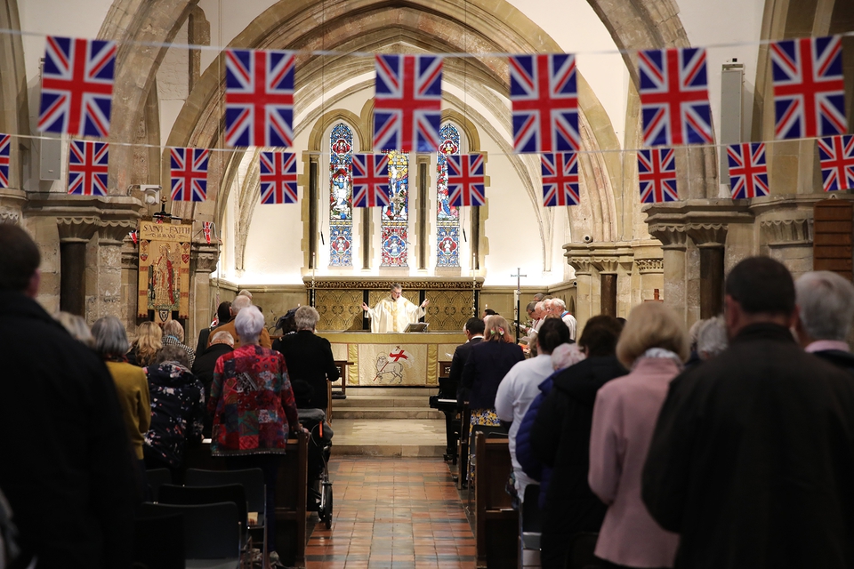 Canon Tom Kennar leads the service in a church bedecked with bunting and flags