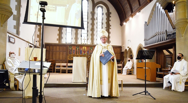 Bishop Christopher leads a socially-distanced service, where attendees are all wearing face masks