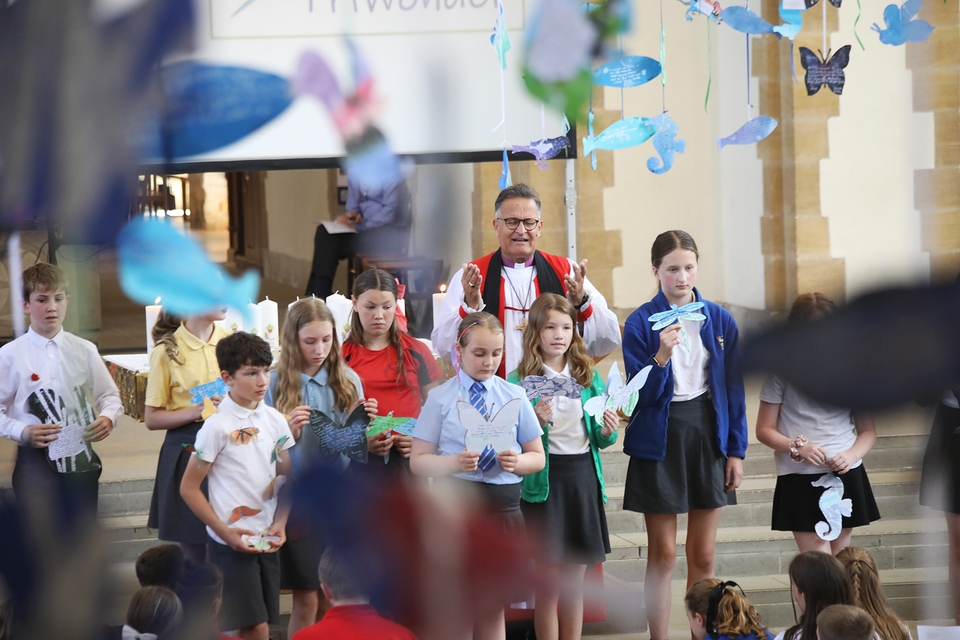 The bishop blesses artwork brought to the front by one pupil from each school represented in that service